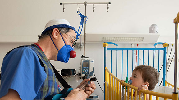 Arzt mit roter Nase bringt Kind zum Lachen